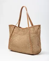 Cartera tipo tote de diseño tejido tipo red color tostado, con asas y detalles en cuero sintético del mismo tono. Incluye un aplique circular frontal perforado con el logo de la marca.