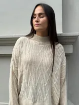 Sweater color crema con cuello alto y diseño de trenzas.