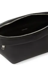 Riñonera negra de poliuretano con correa ajustable con broche. Tiene un bolsillo exterior con cremallera y logo de Calvin Klein en la parte delantera.
