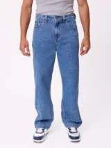 Jean de corte slouchy fit, confeccionado en denim de algodón color azul medio. Presenta diseño de cinco bolsillos, cierre frontal con botón y costuras reforzadas en tono contrastante.