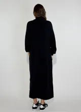 Vestido largo gris de tejido de punto con cuello alto y mangas largas.