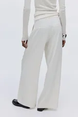 Pantalón de tiro alto con piernas amplias y corte recto. Presenta cierre frontal con botón oculto, bolsillos laterales al bies y bolsillos traseros insertados, con pliegues marcados en la parte delantera y trasera.