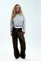 Pantalón cargo de tiro medio confeccionado en denim negro con efecto lavado. Presenta bolsillos laterales con solapa, bolsillos delanteros y traseros, corte recto y cinturón del mismo tejido incluido con hebilla metálica.