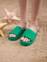 Sandalias tipo chinelas de color verde, con plataforma y capellada de tela texturada estilo toalla con diseño de franjas.