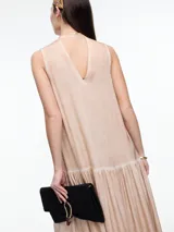 Vestido largo de viscosa en color beige con efecto gastado, diseño sin mangas con escote halter y tira tipo choker para anudar al cuello. Presenta un corte a la altura de la cadera con falda fruncida que aporta volumen y movimiento.