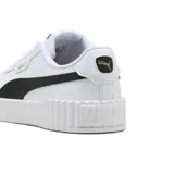 Championes Puma Carina 3.0 de mujer, en color blanco con franja lateral negra y detalles en tono dorado. Cuentan con una suela de plataforma texturizada con diseño acanalado en la parte delantera y trasera.