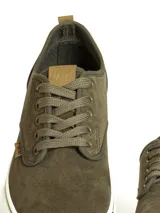 Zapatillas casuales de caña baja, color negro, con capellada de textil y suela de PVC blanca. Presentan cordones negros y detalles en cuero sintético marrón en la lengüeta.