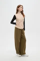 Chaleco negro con diseño capitoneado, cierre frontal con botones a presión y cuello alto.