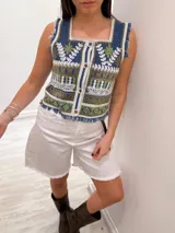 Chaleco corto en denim con bordado artesanal multicolor y escote cuadrado. Con cierre de botones y terminaciones desflecadas.