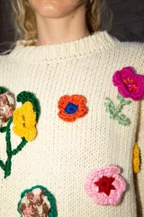 Sweater holgado de lana merino color marfil, con mangas con diseño de ochos y apliques bordados de flores en 3D de diversos colores.