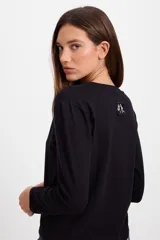 Remera de manga larga color blanco, con cuello redondo y corte holgado. Presenta un pequeño bordado en el centro del pecho.