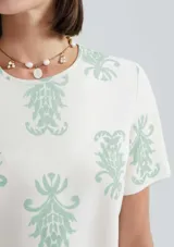 Blusa color salmón con estampado de flores blancas, de mangas cortas con volados y cuello redondo.