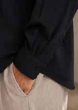 Camisa de diseño clásico con cuello camisero, mangas largas con puños abotonados y cierre frontal de botones.