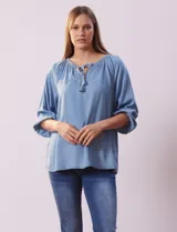 Blusa celeste de tencel con cuello redondo, escote en V y lazo de ajuste. Tiene cuello y escote calado y mangas 3/4 amplias con puño elastizado.