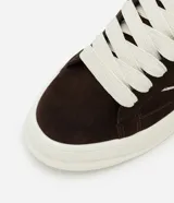 Championes de estilo skater para hombre, confeccionados en poliuretano color marrón oscuro. Poseen punta redonda, caña baja y suela de plataforma blanca. Destacan por sus cordones anchos tipo fat lace y detalles laterales en contraste.