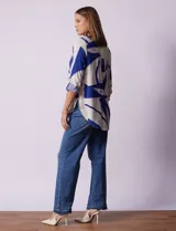 Camisa de manga larga con estampado abstracto en tonos verde y blanco. Cuello con solapa y abertura central con botones. Largo de manga regulable con presilla y botón. Terminación de ruedo anudada opcional.