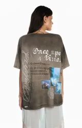 Remera gris de algodón con efecto lavado, corte oversize y estampa frontal gráfica con diseño de alas y texto.