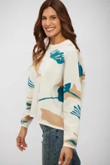 Buzo de tejido de punto con diseño estampado abstracto en tonos beige y turquesa sobre base color crudo, de corte holgado, cuello redondo y mangas largas.