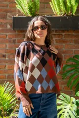 Sweater tejido de algodón con diseño de rombos multicolor en tonos marrones, azul y rojo. Presenta una silueta oversize, cuello redondo y mangas largas abullonadas con puños ajustados.