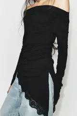 Camiseta de manga larga confeccionada en viscosa, con cuello barco y ajuste slim fit. Presenta un diseño con drapeado lateral y un bajo asimétrico decorado con una aplicación de encaje.