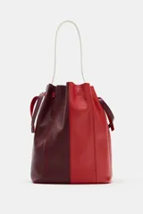 Bolso de hombro formato maxi de piel, en combinación de colores rojo y bordó. Cuenta con detalle de pespuntes, bolsillo interior con cremallera extraíble y cierre mediante fruncido con asas finas de hombro.