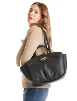 Cartera tote negra de ecocuero con base redondeada y pliegues decorativos. Cuenta con una solapa central con herraje dorado en forma de "T" y asas dobles para hombro y mano. El interior tiene triple compartimento.