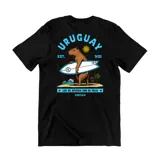 Remera negra de algodón con estampado gráfico en la espalda que muestra un carpincho surfista, el sol de mayo y la leyenda 'Uruguay' y 'Los de afuera son de palo'.