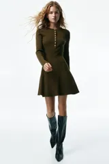Vestido corto de punto acanalado color verde militar, con escote redondo, cierre frontal parcial con botones, manga larga, cuerpo entallado y falda evasé con vuelo.