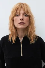 Sweater de pana color marrón con cuello polo y cierre frontal parcial. Presenta un diseño de corte holgado, mangas largas con puños elásticos y textura acanalada.