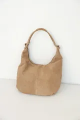 Cartera tipo hobo de cuero color negro, de diseño slouchy, con tiras de hombro sujetas por argollas metálicas plateadas y cierre superior.