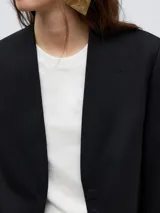 Blazer sastre negro tejido de lana merino, sin solapa y sin bolsillos, de largo bajo cadera y efecto emboss.