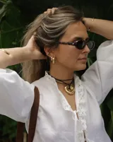 Collar con dije de forma irregular en tonos dorados y plateados, suspendido de un cordón doble de algodón negro.