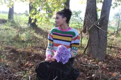 Sweater de lana merino tejido a mano, con diseño de rayas horizontales multicolor en el torso y mangas con detalles en jacquard, cuello redondo y puños en contraste.
