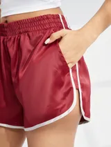 Short deportivo de satén color bordó con cintura elástica y ribetes blancos en los bordes.