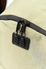 Mochila verde de tela con doble cierre, forro interior textil, compartimento para notebook pequeña y bolsillo externo con solapa.