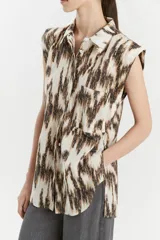 Camisa sin mangas de voile de algodón con estampado abstracto en tonos marrones y blancos. Tiene cuello camisero, cartera con botones a la vista, tajos laterales y bolsillo plaque en el delantero.