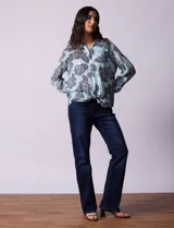 Blusa celeste con estampado de flores grises, de gasa, con cuello con solapa y escote en V, abertura central con botones, bolsillo aplicado y terminación anudada.