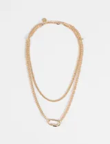 Collar de doble cadena de eslabones finos en tono dorado, con un dije central en forma de mosquetón ovalado.