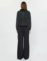Cardigan negro de manga larga con lentejuelas bordadas, cuello redondo y cierre frontal con botones metálicos. Presenta puños y bordes acanalados.