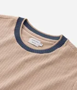 Remera de manga corta, color azul, con textura acanalada vertical. Presenta cuello redondo y puños contrastantes en color beige.