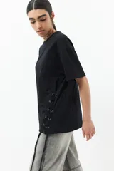 Remera blanca de algodón con cordones ajustables a los laterales, manga corta y cuello redondo.