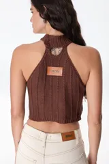 Top de cuello halter confeccionado con parches de cuero negro unidos mediante tejido de punto a crochet, creando un diseño geométrico de rombos.