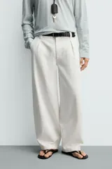 Pantalón barrel fit de hombre, confeccionado en denim de algodón color crudo. Presenta cintura con pliegues frontales, bolsillos laterales y cierre con cremallera y botón.
