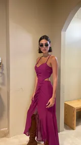 Vestido midi color uva con escote corazón, tirantes finos y aberturas laterales en la cintura. Presenta un diseño con frunces frontales y una falda con tajo lateral.