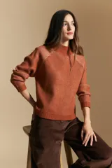 Polera de tejido acanalado en color marrón con detalles de líneas en tono lila, cuello alto y mangas largas con diseño raglán.