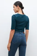 Remera verde de tejido canalé con cuello redondo y media manga. Tiene una abertura frontal con botones.