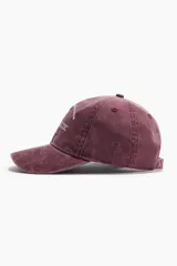 Gorra de sarga de algodón bordada en color bordó, con efecto lavado, visera curva y cierre metálico ajustable en la parte posterior.