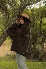 Sweater marrón de tejido de punto grueso con mangas largas y costuras blancas decorativas.