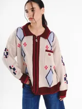 Campera tejida en jacquard con cierre frontal, cuello tipo polo y bolsillos delanteros. Diseño multicolor con estampado geométrico de rombos y detalles bordados a mano.