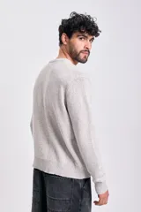 Sweater de tejido de punto color gris claro jaspeado, con cuello redondo y manga larga.